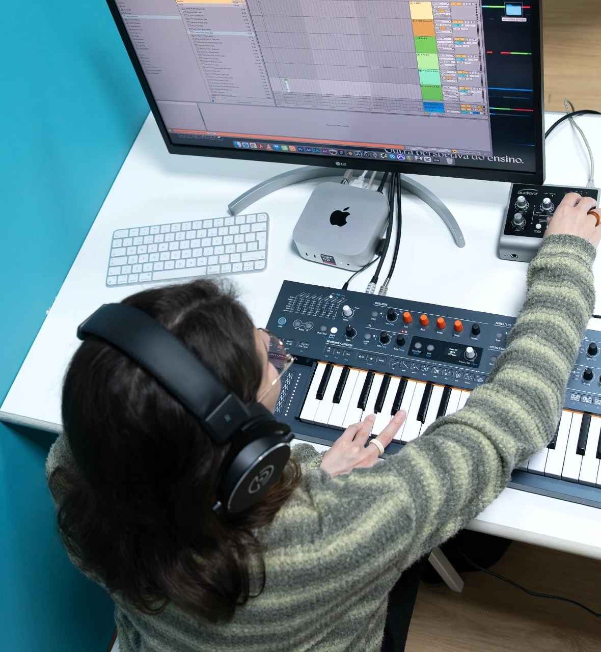 Aula prática do Curso Criação Musical Produção e Técnicas de Som, com formanda a trabalhar num teclado MIDI e software de áudio.